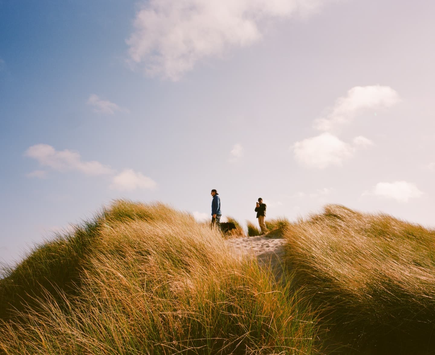 Film photograph — two people on shared ground, looking outward